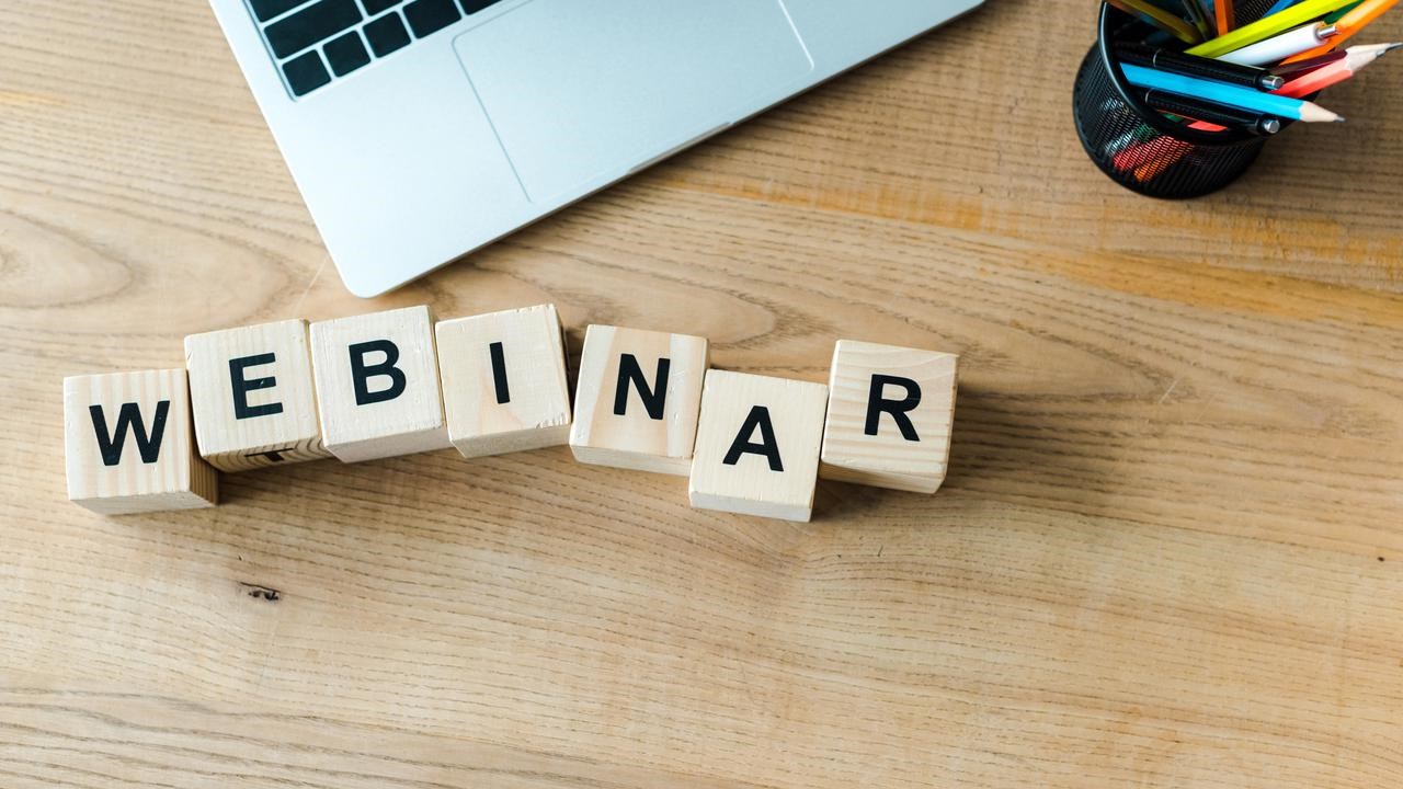 Träklossar på skrivbord bredvid laptop som bildar ordet webinar.