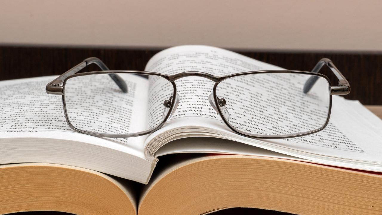 Läsglasögon på en uppslagen bok.