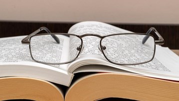 Läsglasögon på en uppslagen bok.