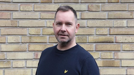 Porträtt av man framför tegelvägg