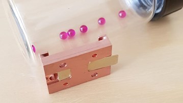 En glasburk fylld med rosa pärlor på ett bord.