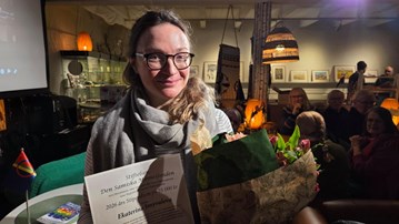 En kvinna som håller i en blombukett i ett rum fullt av människor.