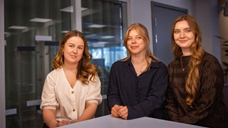 En grupp med tre studenter som sitter bredvid varandra.