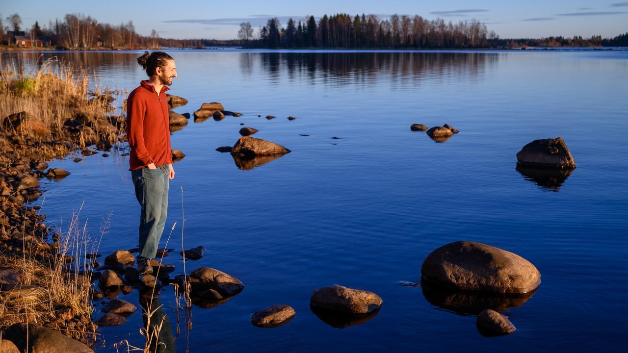 A man standing on a rocky shore next to a body of water