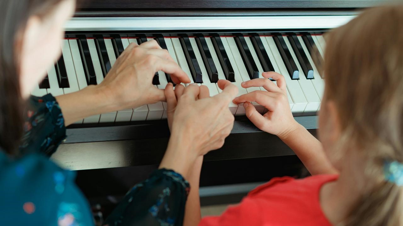 En lärare och elev som spelar piano tillsammans.