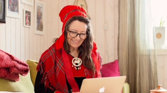 En kvinna sitter i en soffa och använder en bärbar dator.