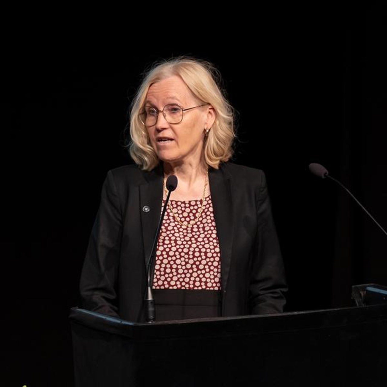En kvinna står på ett podium framför en mikrofon.