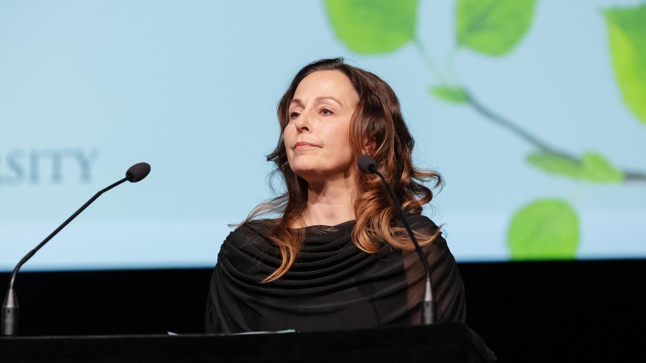 En kvinna står på ett podium framför en projektionsskärm.