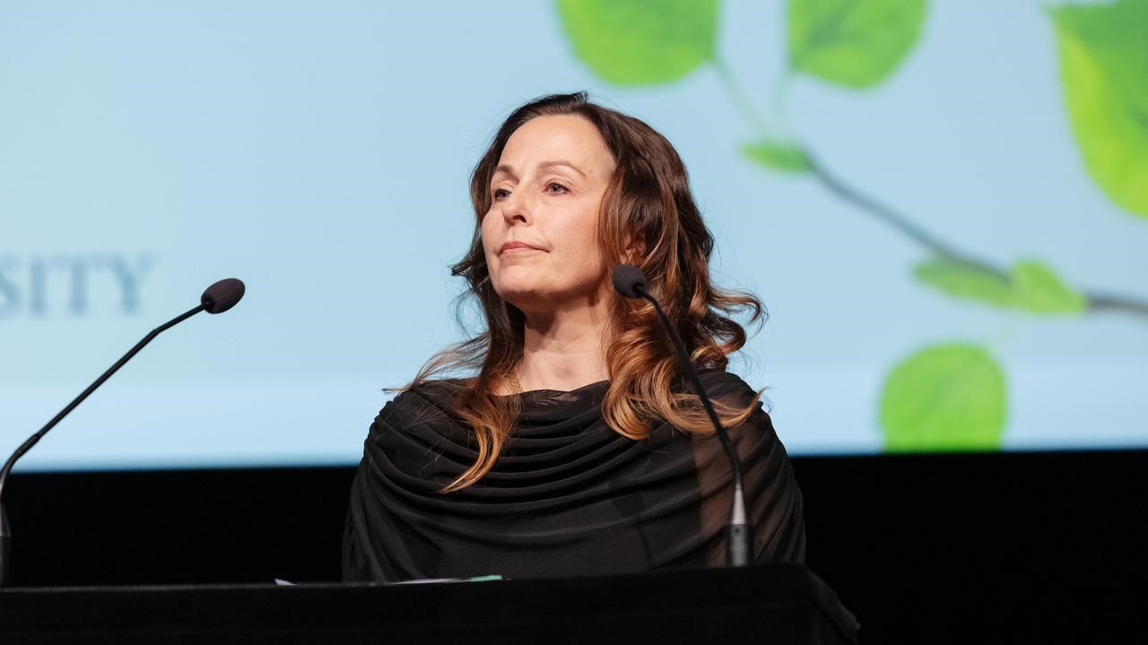 En kvinna st&aring;r p&aring; ett podium framf&ouml;r en projektionssk&auml;rm.