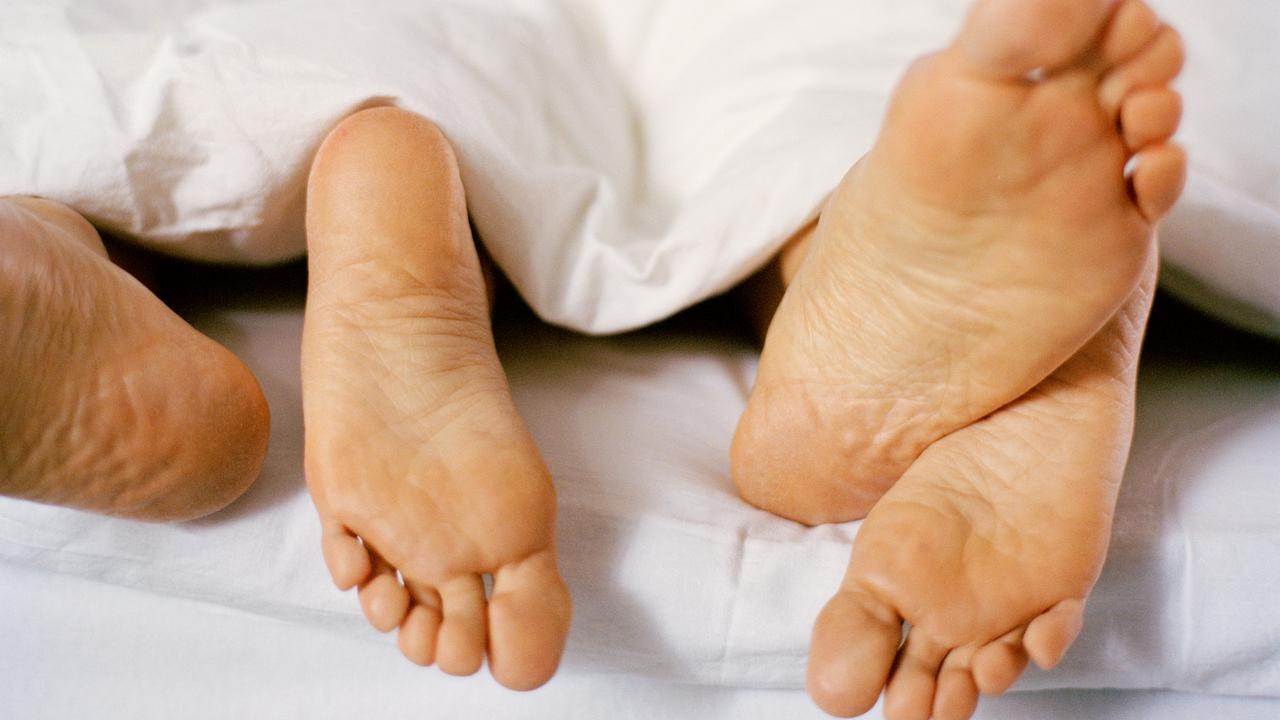 Fyra fötter sticker fram under täcke