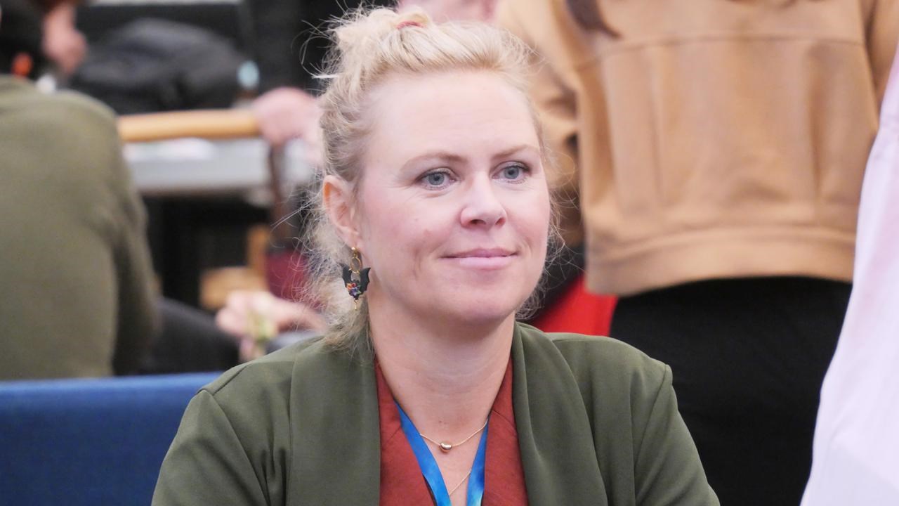 En kvinna som sitter på en blå soffa framför en grupp människor.