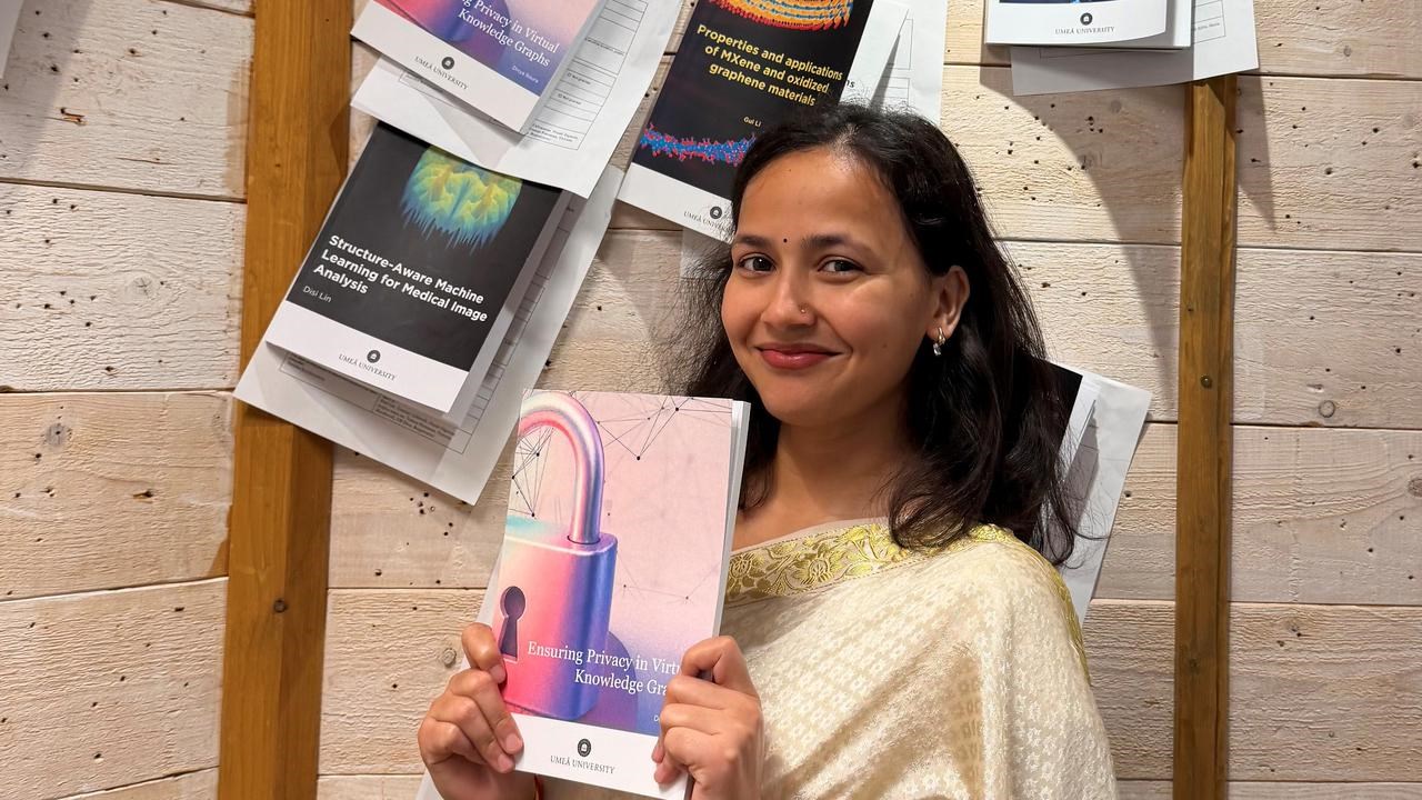 Divya Baura, i m&ouml;rkt h&aring;r och fin kl&auml;dsel, h&aring;ller upp sin avhandling under spikningsceremonin.