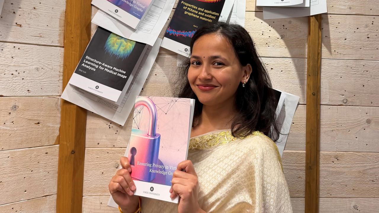 Divya Baura, i m&ouml;rkt h&aring;r och fin kl&auml;dsel, h&aring;ller upp sin avhandling under spikningsceremonin.