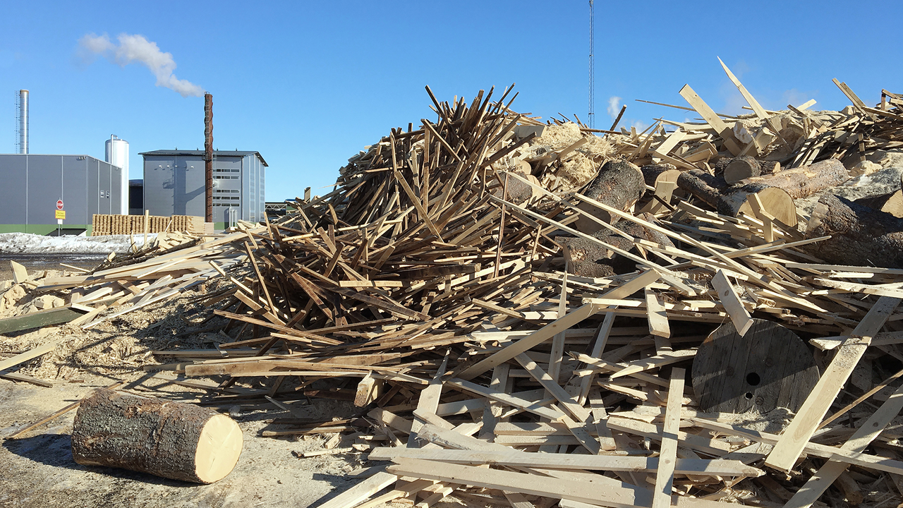 Wood debris at the ground, and a factory in the background