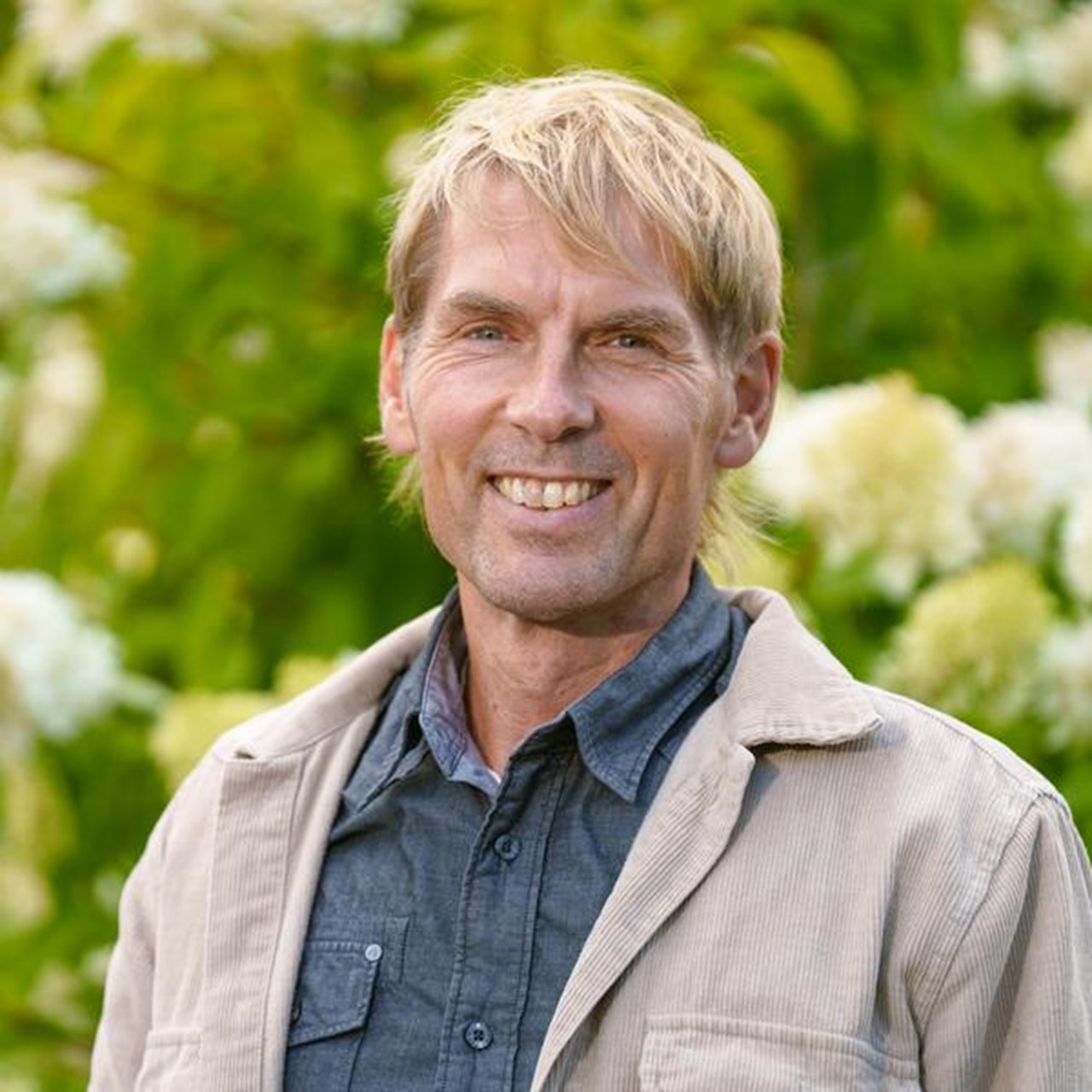 Man som st&aring;r utomhus framf&ouml;r en blommande buske