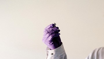 A gloved hand holds an item in a lab.