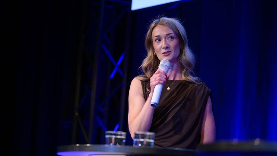 Olivia Lundin står vid ett talarstativ med en mikrofon.