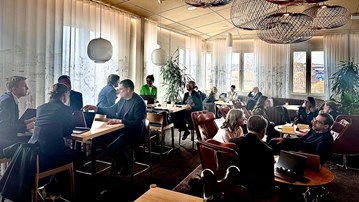 grupp av människor diskuterar vid olika bord