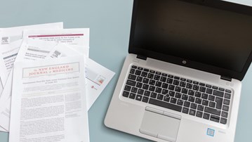 Vetenskapliga artiklar bredvid bärbar dator
