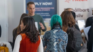 People standing in front of exhibitioners at a fair.