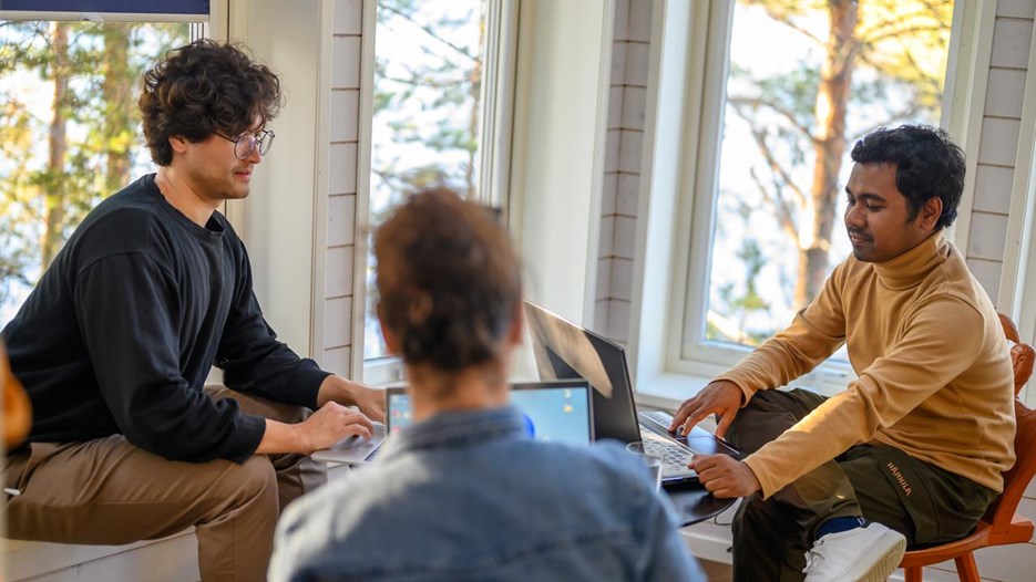A group of people sitting around working on laptop computers.