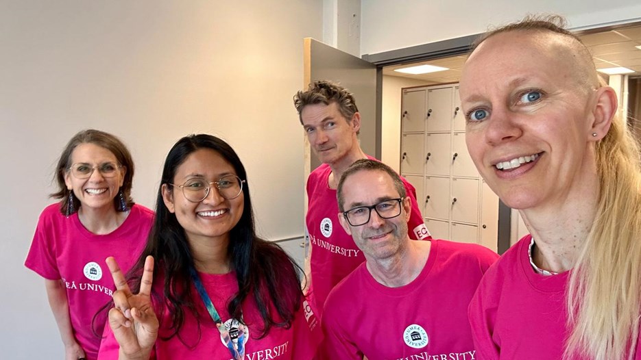 En grupp människor i rosa skjortor som poserar för en bild.