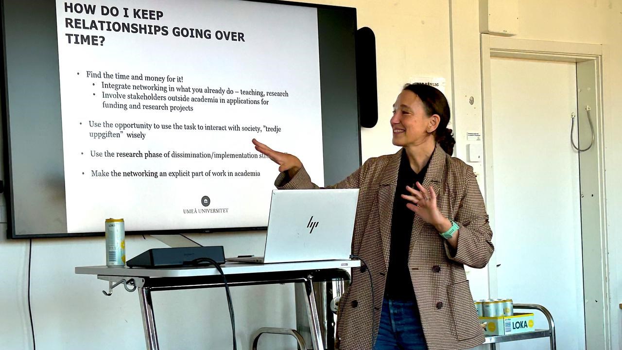 En kvinna som står framför en projektorskärm och håller en presentation.
