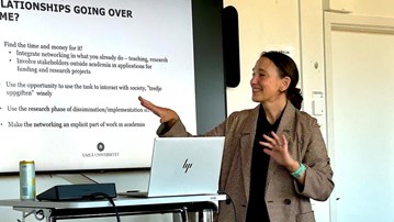 En kvinna som står framför en projektorskärm och håller en presentation.