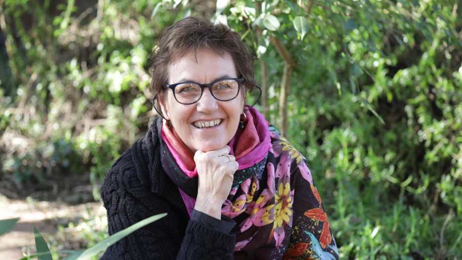 A woman wearing glasses is sitting on a bench.