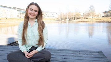 Porträttfoto på Johanna Birgersdotter, i bakgrunden dammen på campus.