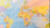 Bild på världskarta, anteckningsblock, solglasögon och kamera för att illustrera resa eller internationalisering.