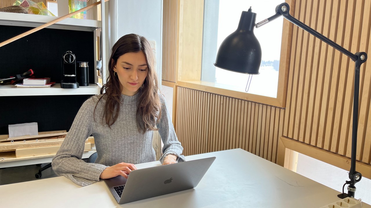 Emma Biondani sitter vid sitt skrivbord på Arkitekthögskolan och skriver på sin laptop.