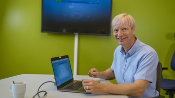 Kary Främling, professor i datavetenskap, sitter framför skärmar i ett grönt arbetsrum