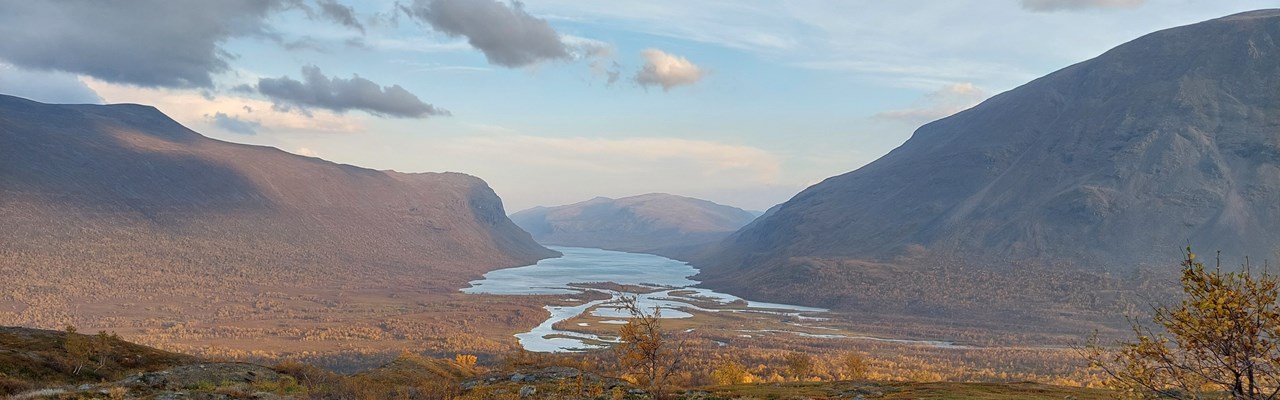 Vy över vattendrag genom fjällandskap.