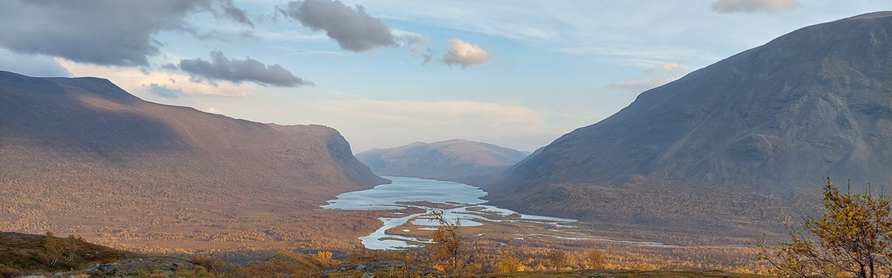 Vy över vattendrag genom fjällandskap.