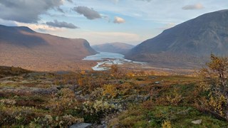 Vy över vattendrag genom fjällandskap.