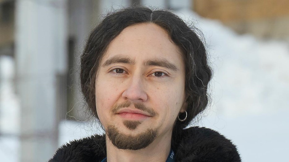 A man standing in front of a building wearing a black jacket.