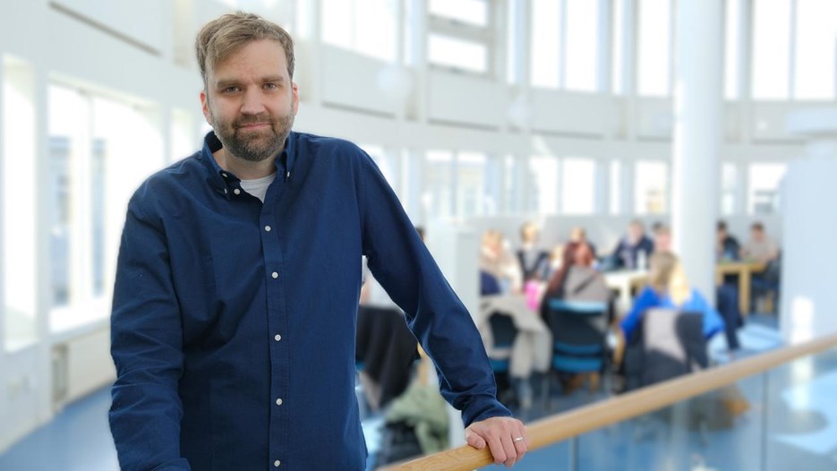 En man i blå skjorta står vid ett räcke.