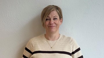 Kvinna står framför vägg och ler