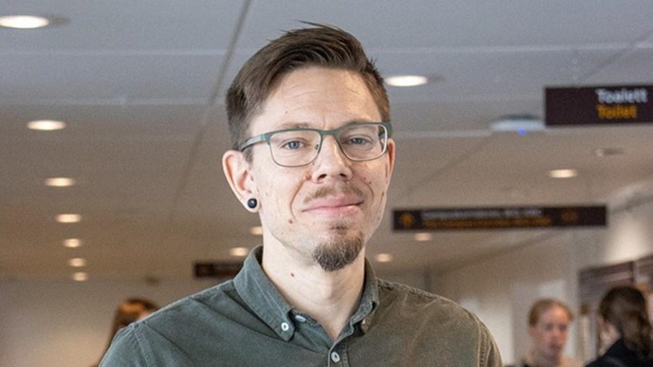 En man i grön skjorta står på en flygplats.