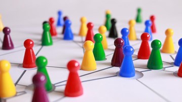Olikfärgade spelpjäser i plast placerade på ett underlag med markeringar för att illustrera nätverk.