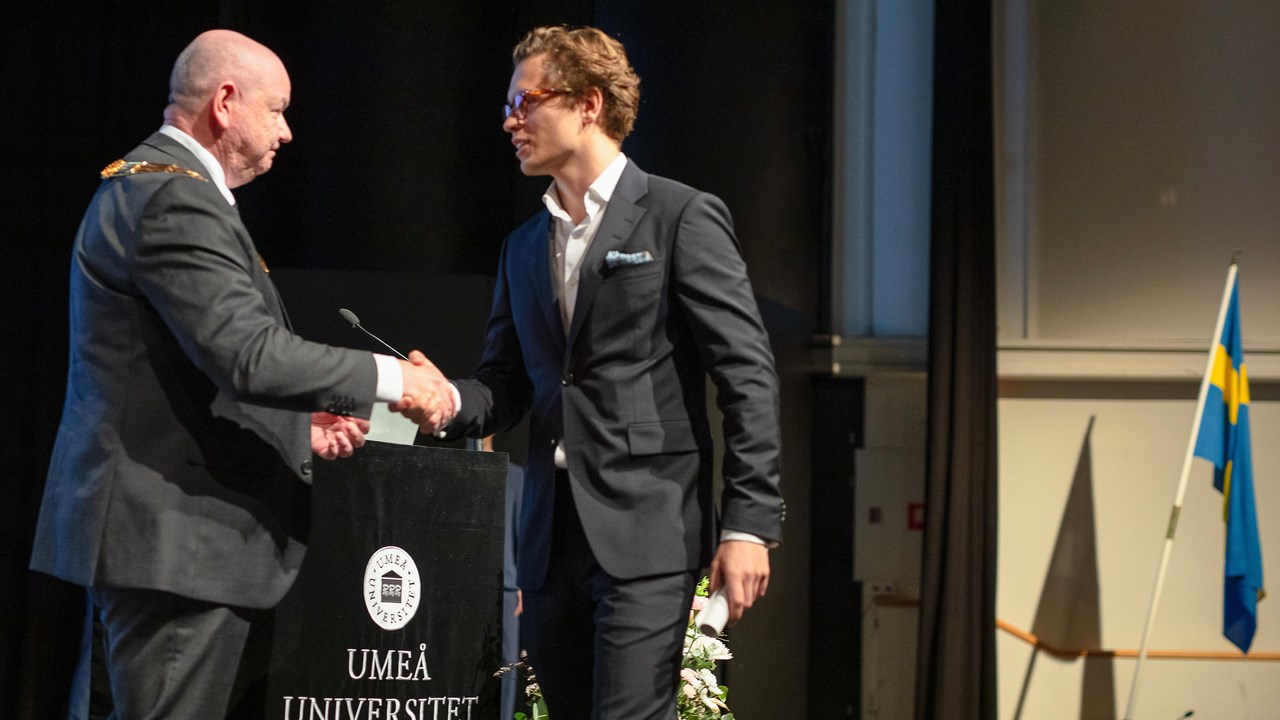 Oskar Fransson tar emot diplom av rektor Hans Adolfsson vid examensceremonin för masterstudenter.
