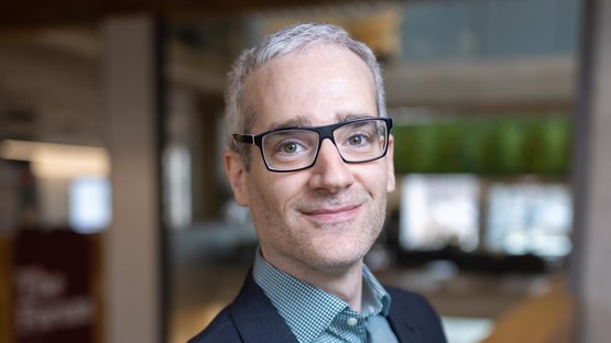 A man in a suit and glasses posing for a picture.