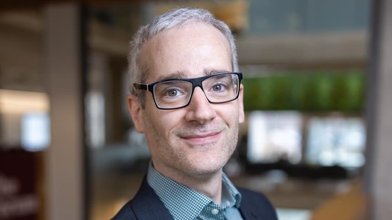 A man in a suit and glasses posing for a picture.