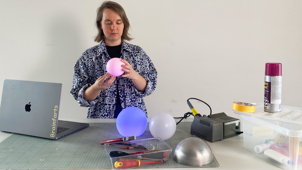 Ilse Pouwels står vid sitt skrivbord och håller i en rosa ballong