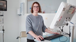 Kvinna står framför dator på högt bord.