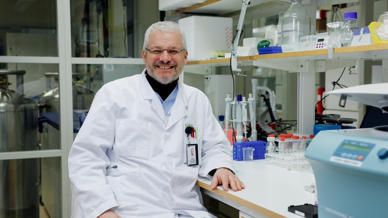 Gruppledare Peter Andersen sitter vid en labbänk i sitt labb och ler glatt.