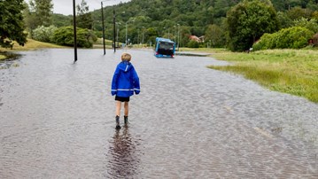 Pojke går på översvämmad gata