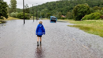 A boy standing on a floaded street