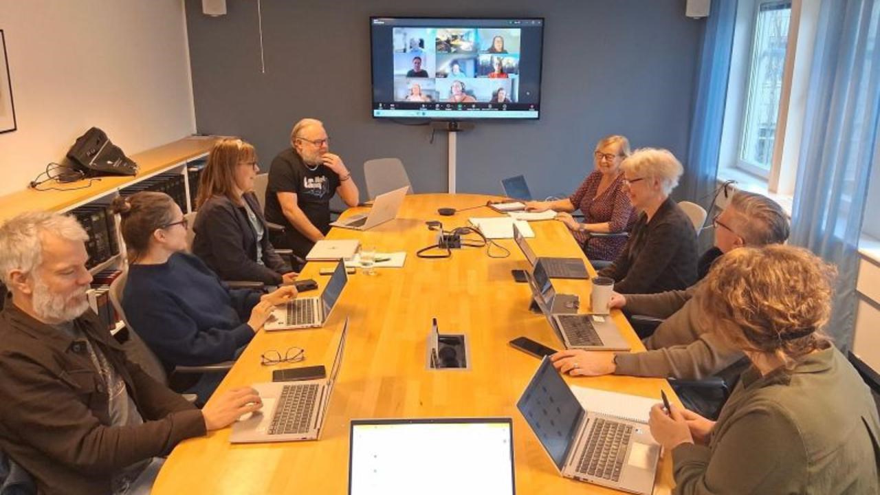 En grupp m&auml;nniskor som sitter runt ett bord med b&auml;rbara datorer.